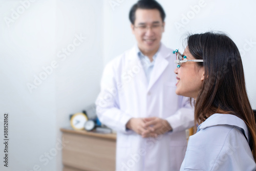 Asian woman with a trial frame to test her vision, optometrist takes care of her side, selective focus