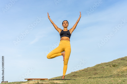 Middle-aged woman practicing yoga outdoors in the middle of the bush