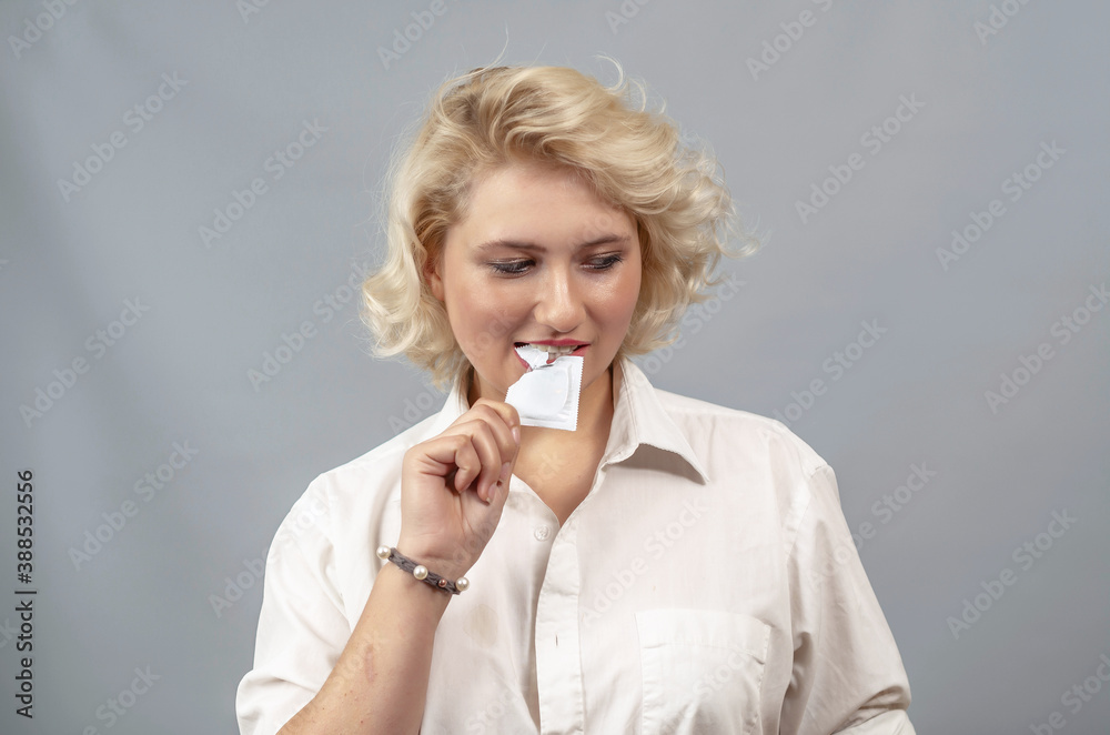 Young woman opens a condom package with her teeth, preparing for sexual intercourse Young woman opens a condom package with her teeth, preparing for sexual intercourse