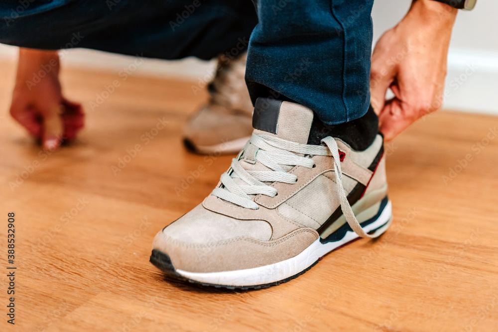 A man puts on sneakers and ties his shoelaces A man puts on sneakers and ties his shoelaces