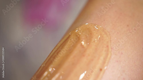 Depilation master woman applying sugar paste on the leg during the procedure of epilation.