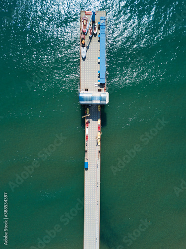 Aerial top view of boats standing on the pier, floating parking of boats on walkway in the turquoise sea water. Sochi, Russia
