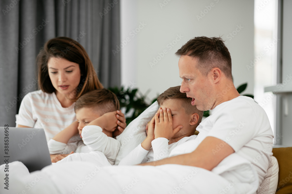Beautiful parents with kids enjoying at home. Young family watching movie on lap top.. Beautiful parents with kids enjoying at home. Young family watching movie on lap top..