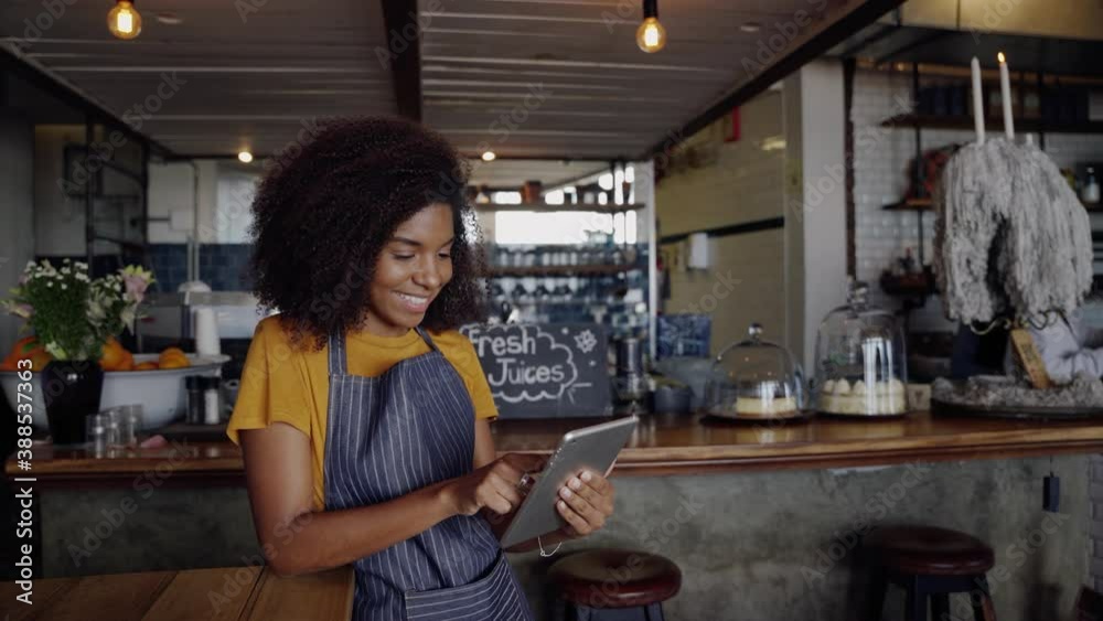 Beautiful waitress using face ID to unlock tablet standing in funky cafe 