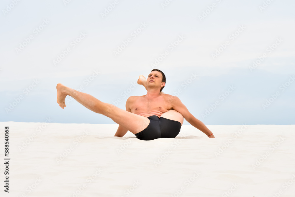 Young man doing yoga stretching on the beach