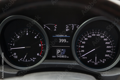 The dashboard of the car is glowing white with arrows at night with a speedometer, charge battery level and volume of oil in the engine to monitor the condition in modern style on black isolated.