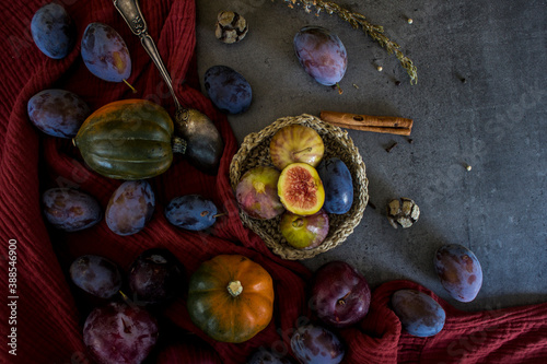 Fresh fruits and vegetables on a table: plums, grapes, pumpkin and figs. Autumn mood still life. 