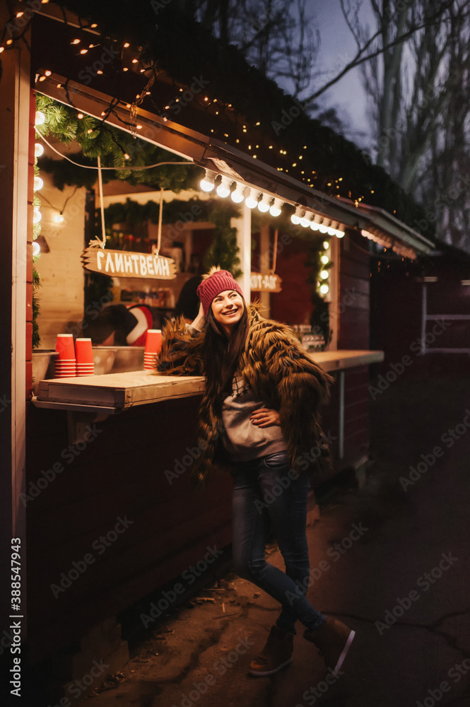 The beautiful young lady standing near Christmas market counter 