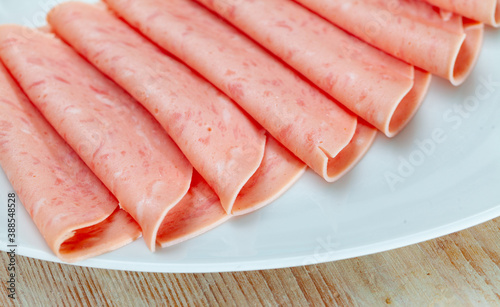 Closeup of sliced tasty ham on white plate