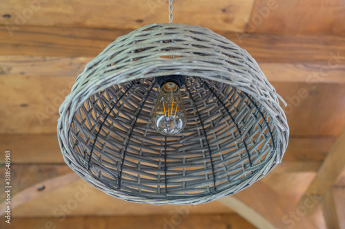 Gray lamp with a light bulb hanging on the background of a wooden ceiling