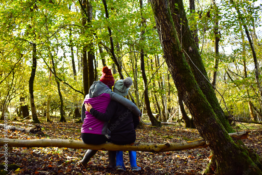 Autumn scene of two children sitting on a log in the woods Autumn scene of two children sitting on a log in the woods