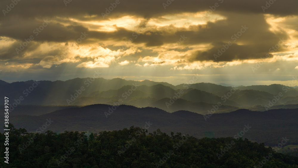Golden Sun ray through cloudy sky with long mountain range in Tak, Thailand Golden Sun ray through cloudy sky with long mountain range in Tak, Thailand
