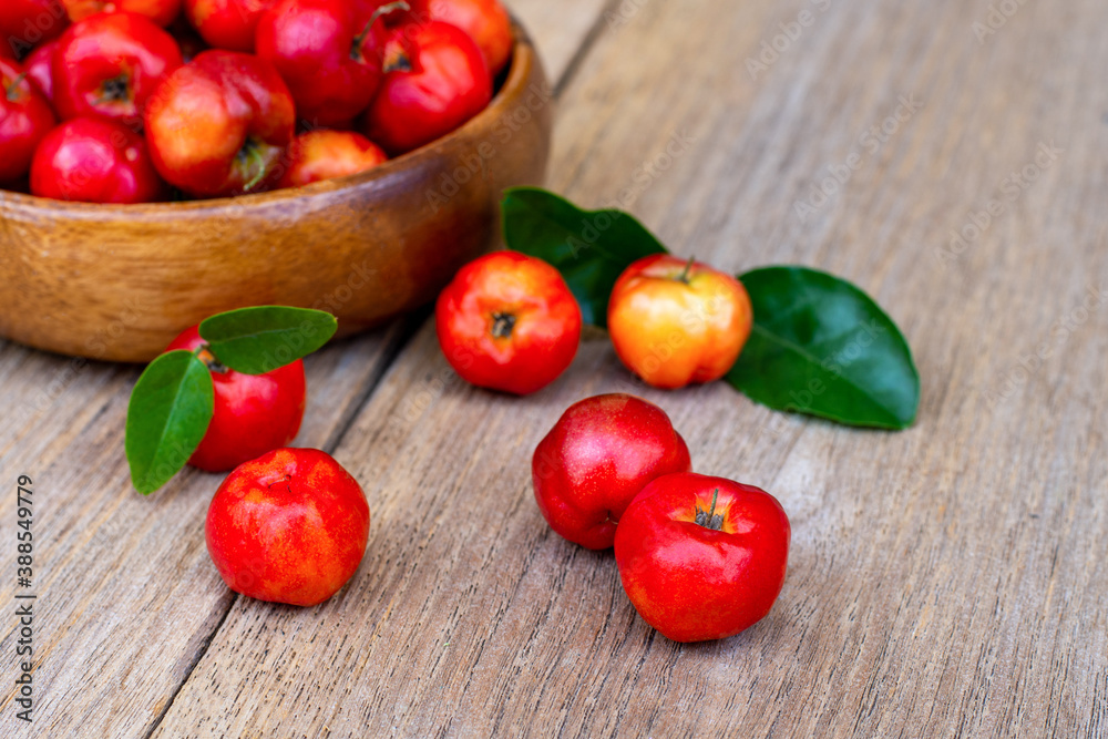 acerola cherry fruit with green leaf in wooden bowl isolated on white background. acerola cherry fruit with green leaf in wooden bowl isolated on white background.
