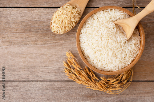 rice in a wooden spoon and bowl on wooden table background.