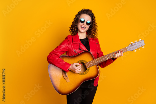 Portrait of attractive cheerful famous wavy-haired girl playing guitar singing isolated bright yellow color background