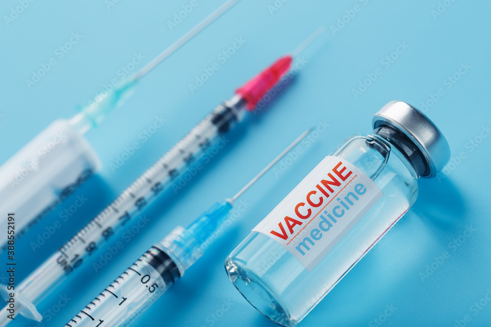 Ampoule of vaccine medicine with a syringe on a blue background. Ampoule of vaccine medicine with a syringe on a blue background.