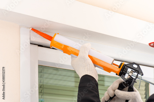 Foto Technician man hand using glue gun, silicone tube or manual caulking gun