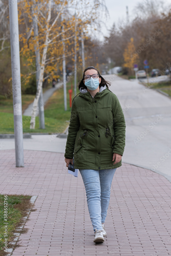 A masked girl is walking along the street. Coronavirus infection (COVID-19) A masked girl is walking along the street. Coronavirus infection (COVID-19)