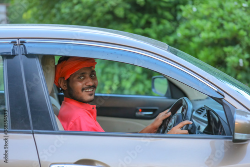 Happy young indian farmer driving new car