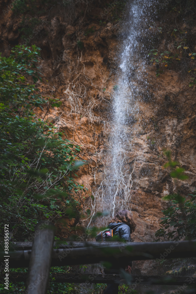 Naklejka premium Joven senderista observando la caída del agua. Young hiker observing the falling water.