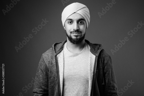 Behang Young bearded Indian Sikh man wearing turban against gray background