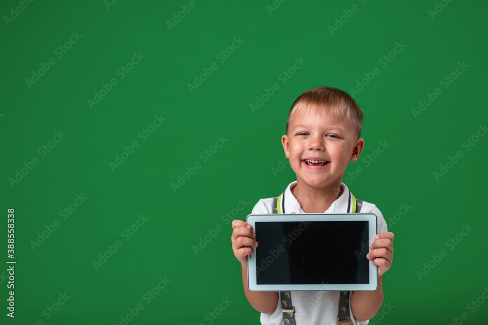 small boy with shows off new computer tablet by pointing at green background small boy with shows off new computer tablet by pointing at green background