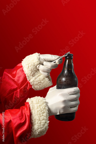 Santa Claus opening a beer bottle. Coloured background and seletive focus.