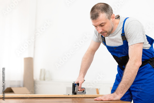 Professional Carpenter Working Using Staple Gun Making Furniture Standing Indoors