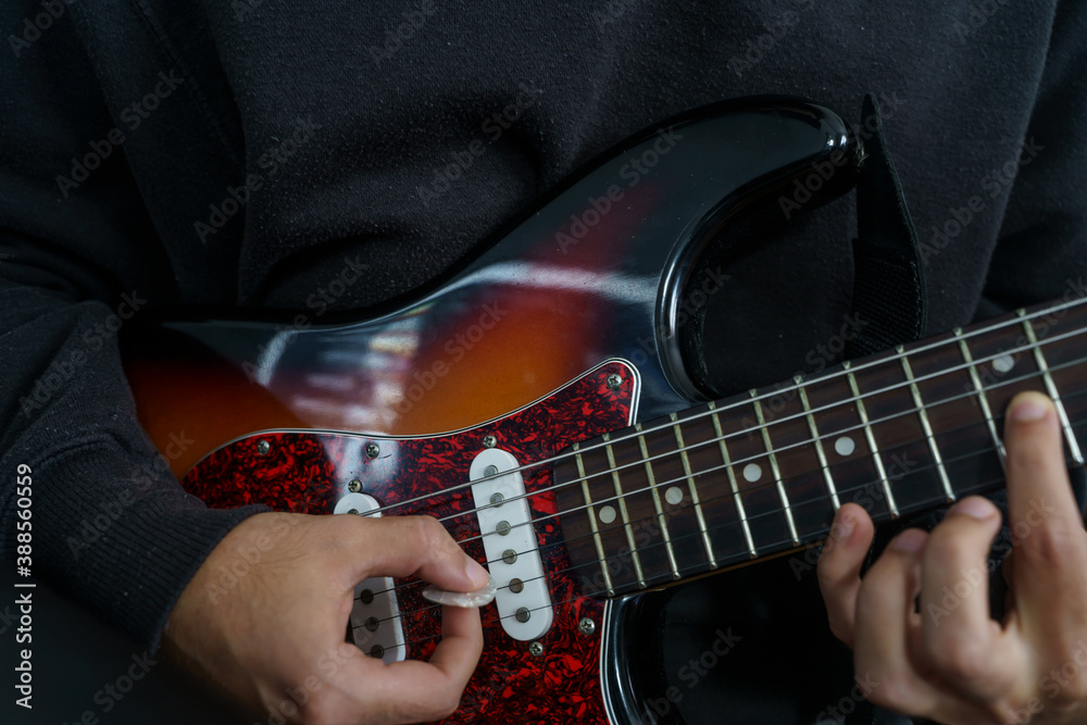 Fototapeta premium Boy playing a beautiful electric guitar of various colours with his hands