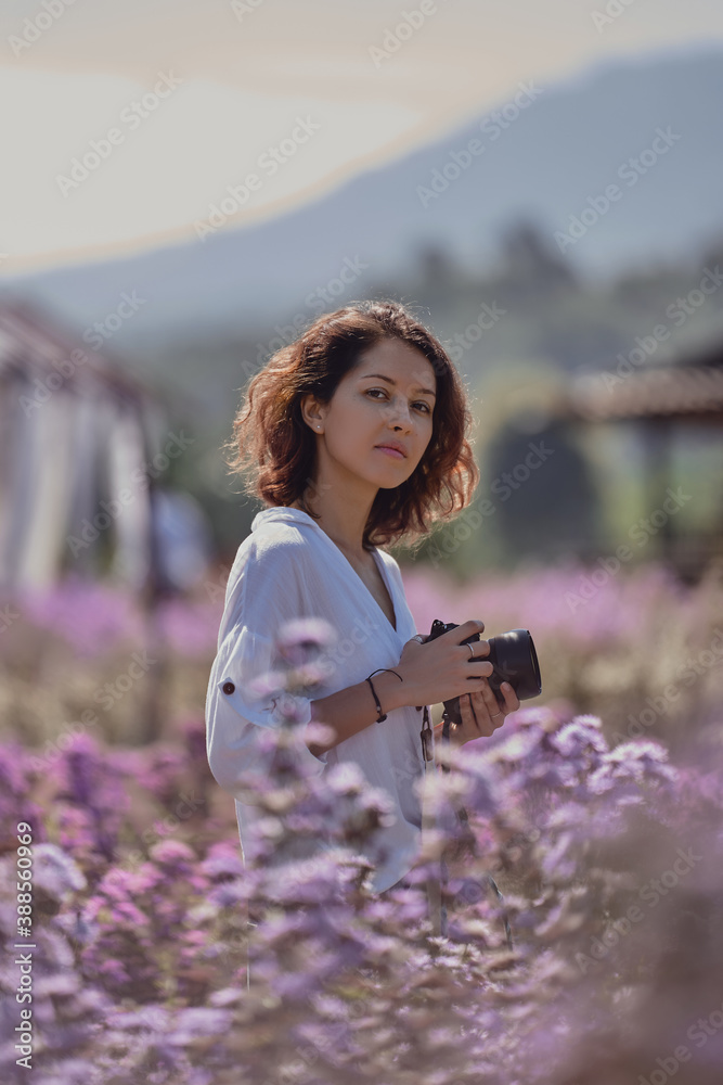 woman professional photographer on a flower field in summer