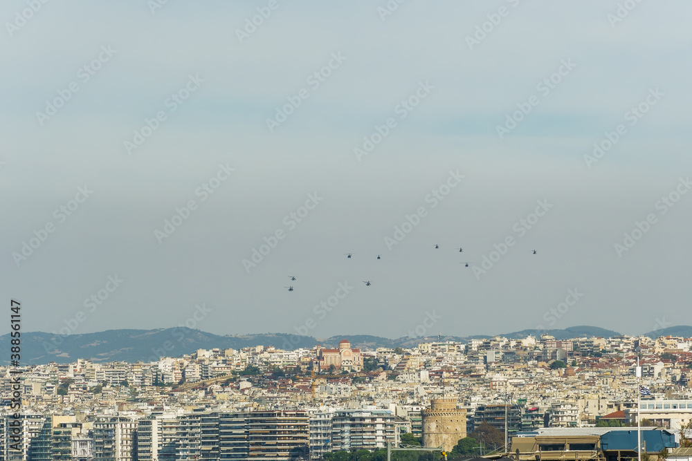 Military helicopters flying above a city. Greek Air Force AH-64 Apache, Kiowa Warrior & Huey UH-1H on formation in Thessaloniki at October 28 commemorating Hellenic no against Italian 1940 ultimatum.