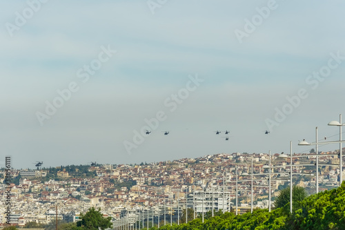 Military helicopters flying above a city. Greek Air Force AH-64 Apache, Kiowa Warrior & Huey UH-1H on formation in Thessaloniki at October 28 commemorating Hellenic no against Italian 1940 ultimatum. photo