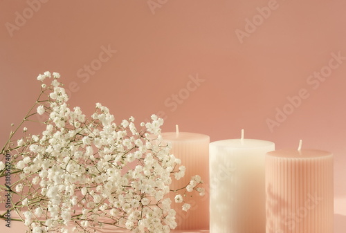 pink candles with white gypsophila flowers on pink  background with copy spac...