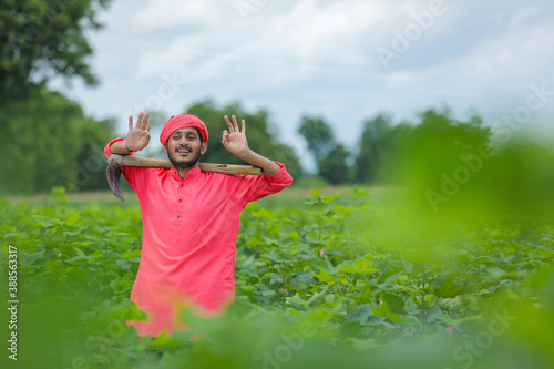 Young indian farmer holding farm equipment in hand at cotton field photo