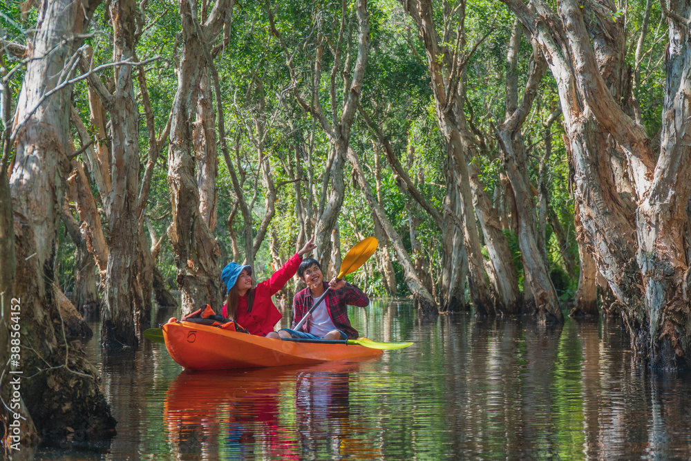 Asian tourists, women and men canoe or kayak in mangrove forests. Rayong Botanical Garden, tropical mangrove forest in a national park in Thailand. Holiday travel activities
