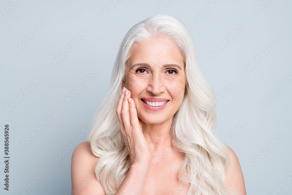 Close-up portrait of her she attractive lovely cheerful grey-haired elderly lady touching cheek smooth skin isolated on gray pastel color background Close-up portrait of her she attractive lovely cheerful grey-haired elderly lady touching cheek smooth skin isolated on gray pastel color background