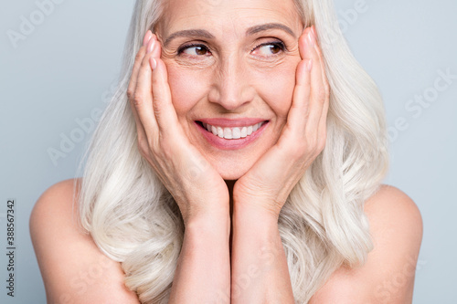 Photo of beautiful aged woman white hair lady look side empty space arms cheekbones isolated grey color background
