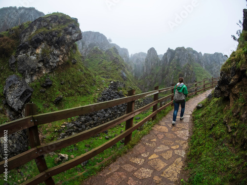Joven camina por un camino de piedra entre los riscos del Parque natural de los Picos de Europa.