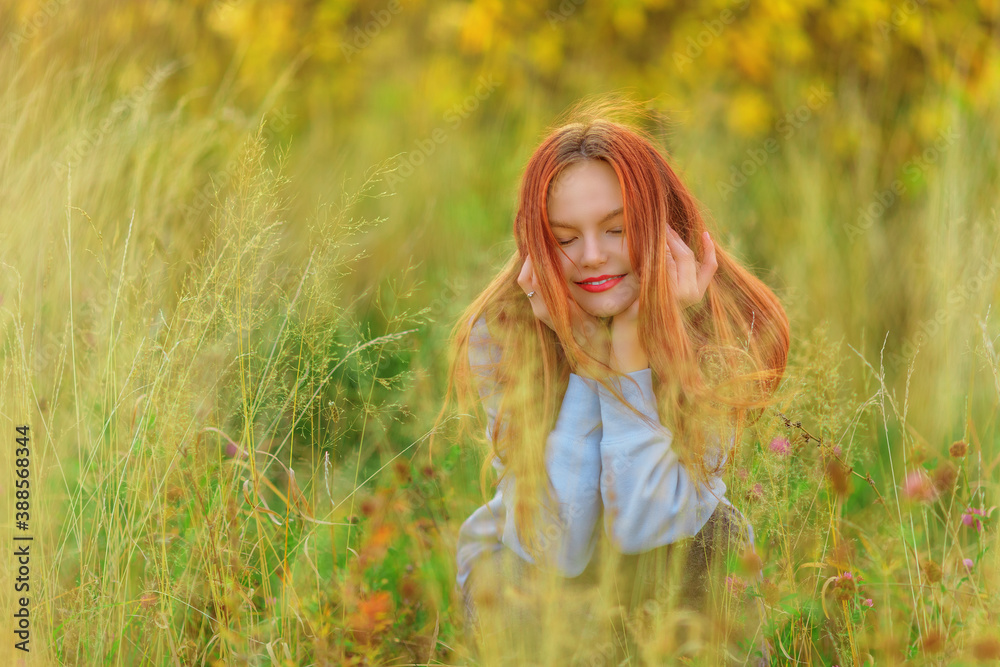 Smiling teen girl in sweatshirt among the grass Smiling teen girl in sweatshirt among the grass