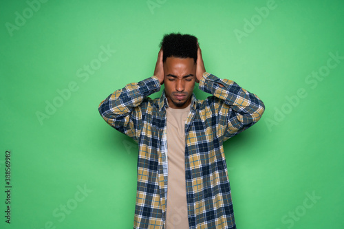 African american man with green shirt having doubts while scratching head isolated on green background © F8  \ Suport Ukraine