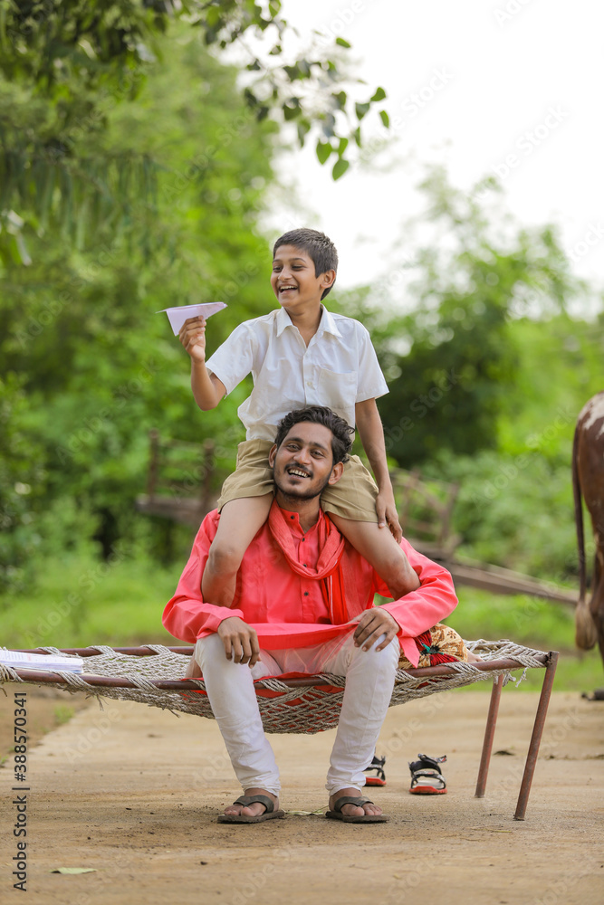 young indian farmer with his child playing with handmade paper airplane