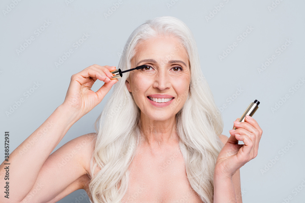 Photo of beautiful retired woman applying brush eyelashes cover extra long flirty lashes isolated grey color background Photo of beautiful retired woman applying brush eyelashes cover extra long flirty lashes isolated grey color background