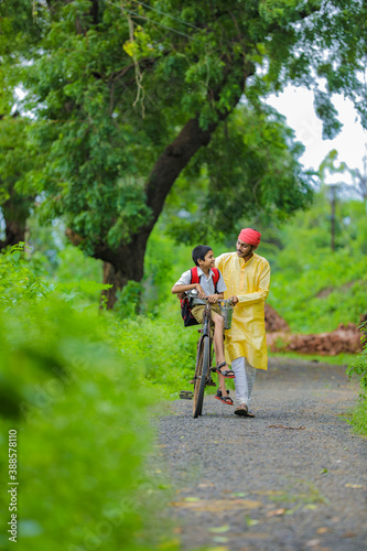 Young indian farmer and his son going to school on cycle
