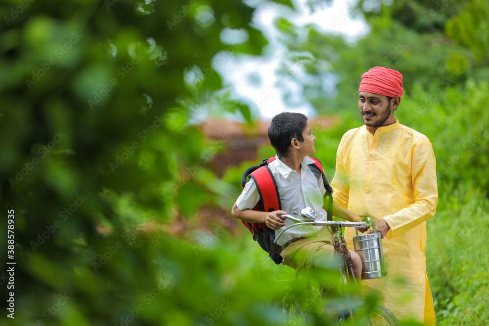 Young indian farmer and his son going to school on cycle Young indian farmer and his son going to school on cycle