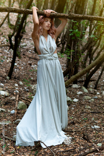 A woman in a white dress in the middle of the forest