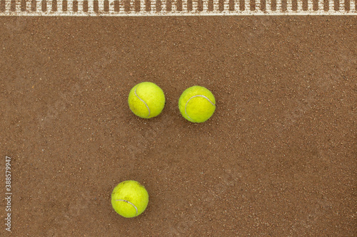 Three tennis balls lie side by side on a red clay court along. View from above. © Сергей Тарантино
