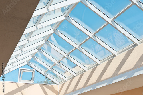Transparent glass roof on top of a modern building. Corporate building corridor with natural light. View from below 