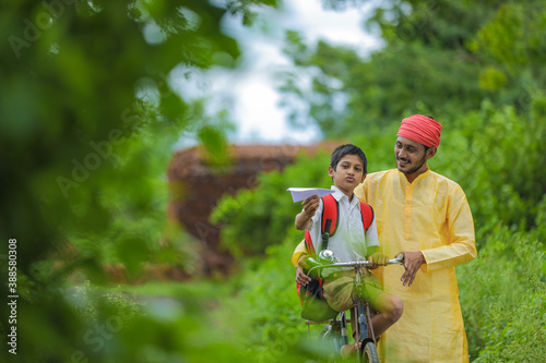 Young indian farmer and his son going to school on cycle