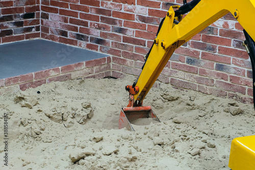 Large childrens yellow excavator in the playroom sandbox