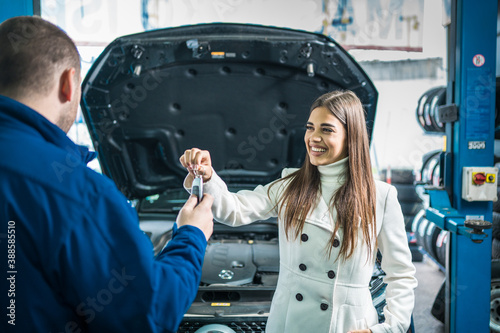A female client giving keys to car mechanic in the garage